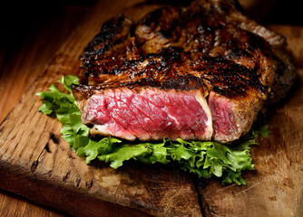 Steak with herbs and beer on a wooden background