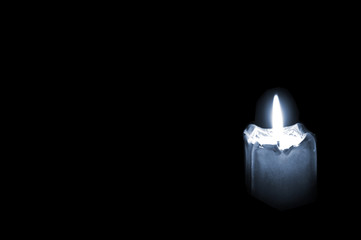 Glowing mourning candle on black background with empty space for text.