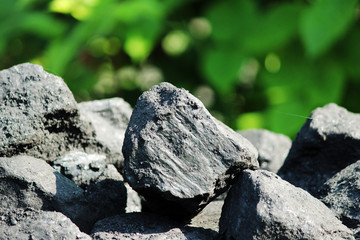Black shiny faceted pieces Charcoal lies on a background of green grass