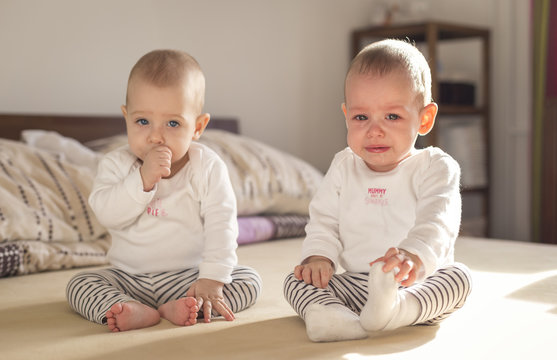 crying baby sitting on a bed