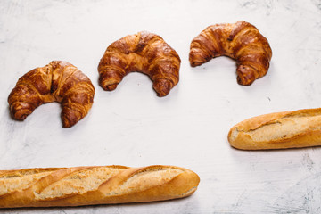 Food background: Freshly baked baguette and croissants on white texture table with copyspace
