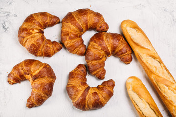 Food background: Freshly baked baguette and croissants on white texture table with copyspace
