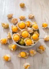 Fresh Cape gooseberry in white bowl and on wooden board