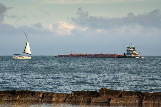 A sailboat and a barge in the Corpus Christi Harbor