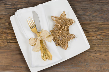 Festive dinner table setting with gold cutlery and stars on rustic wooden table.
Golden wedding anniversary theme.