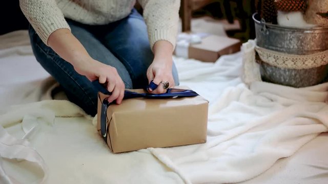 Young Woman Wrapping Christmas Gifts With Brown Paper at Home