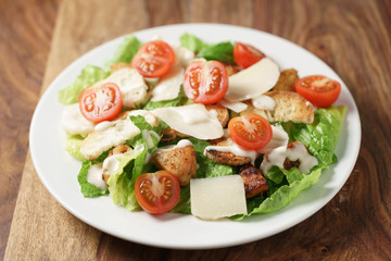 caesar salad with cherry tomatoes on wooden table