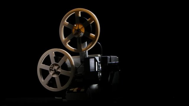 Retro projector showing film. Studio black background