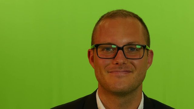 close up of  young businessman wearing glasses against green screen background.
