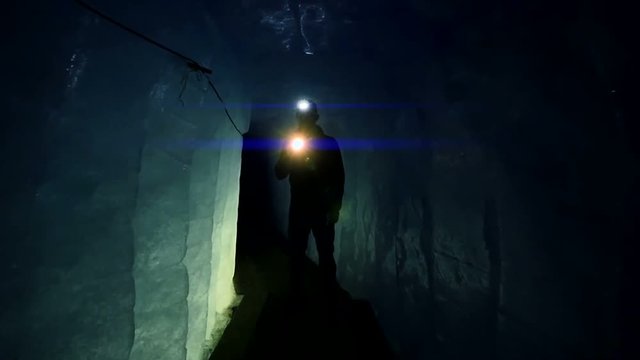 researcher discovering ice inside glacier cave tunnel holding flashlight. global warming background.