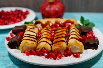 Pancakes with cottage cheese, chocolate sauce, whole grains pomegranate and chocolate cubes. Tasty appetizing dessert