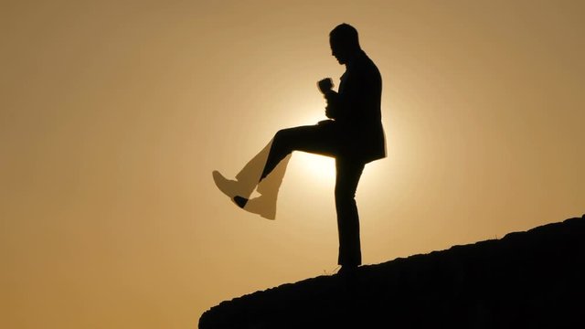 man shadowboxing kicking boxing outdoors. sunset silhouette shadow.