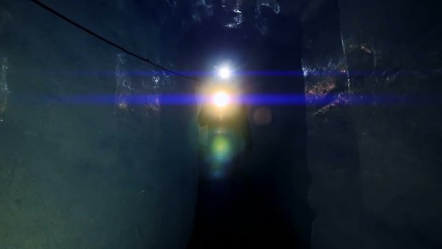 man walking through ice tunnel discovering glacier cave using a flashlight.
