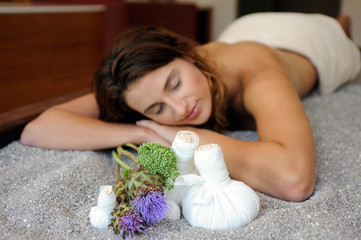 Junge Frau entspannt sich vor einer Quarzstempel-Massage auf einer Quarzssandliege in einem Spa