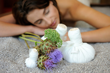 Junge Frau entspannt sich vor einer Quarzstempel-Massage auf einer Quarzssandliege in einem Spa