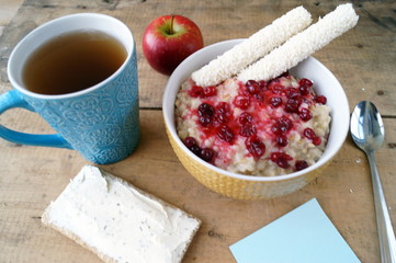 Healthy breakfast, vegetarian. Oatmeal with cranberries, apple, sandwich with cream cheese, coconut sticks, tea.