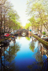 Obraz premium Bridge over canal with mirror reflections in water, Amstardam, Netherlands, retro toned