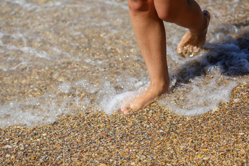 Legs  of woman walking near shore waves