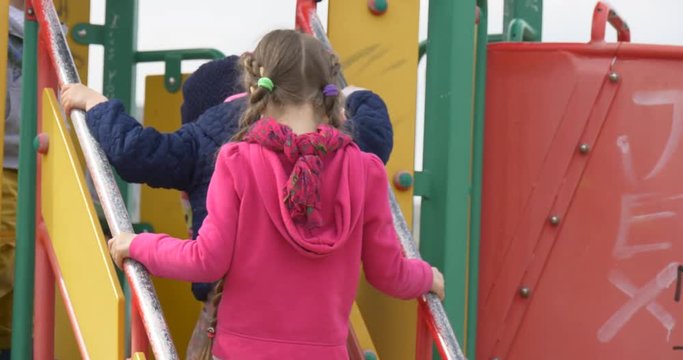 Kids Are Climbing up the Chute Blonde Girl and Boy Chute is Painted in Red and Yellow Colors Green Lawn Park Playground Families Spends Their Weekends