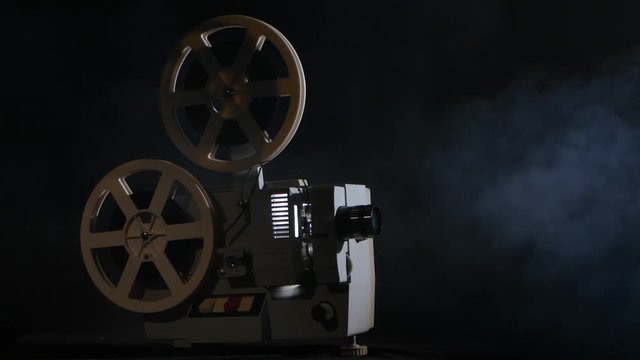 Projector displays movies in the smoke. Black background