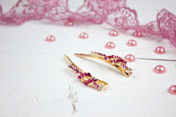 Gold hair accessories with pink lace and pink pearls on white wood