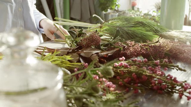 florist hands lying on the table with exotic twigs for bouqet