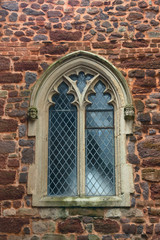 A window in a beautiful frame. Stone wall of an old English church