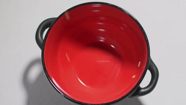Couscous pours cereal into a red bowl in slowmotion