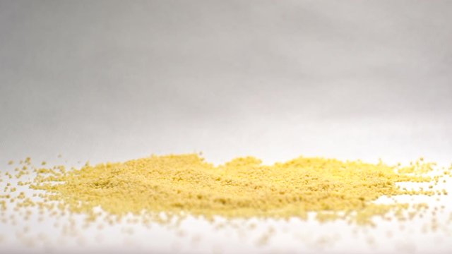 Couscous pours cerealon white background in slowmotion