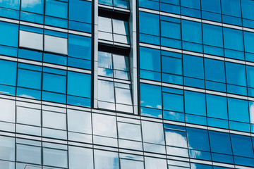 Office building with blue mirrored windows and reflection of clo