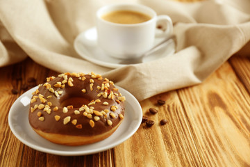 Plate with donut and cup of coffee on background