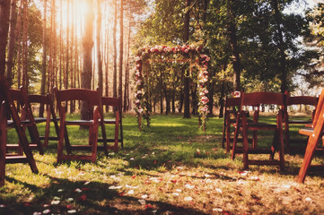 wedding arch decorated with flowers in green forest. 