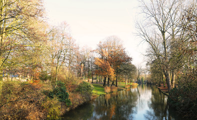 Picturesque autumn landscape with bright blue sky, yellow leaves and steady river in Brugge, Belgium