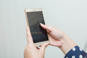 hand of young cute Asia woman is holding her mobile phone  on light white background .