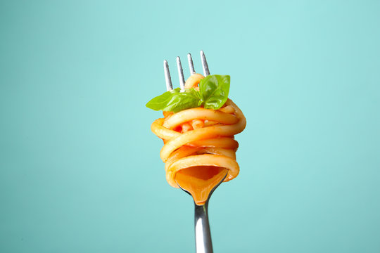 Fork with tasty pasta and basil on color background, close up view