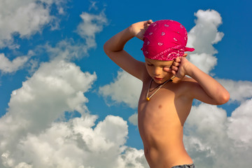 Teenager in crimson bandana hot sunny day on the background of sky and clouds