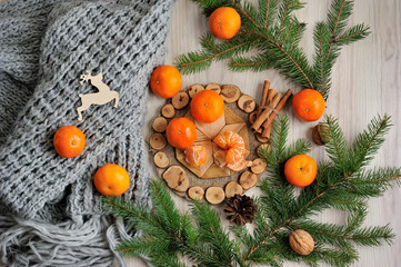 Fototapeta na wymiar Tangerines, scarf and spruce branches on a wooden table