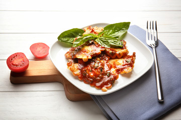 Plate of ravioli with tomato sauce on table