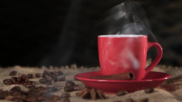 Сup of hot coffee spreads a pleasant fragrance in the room. Black background