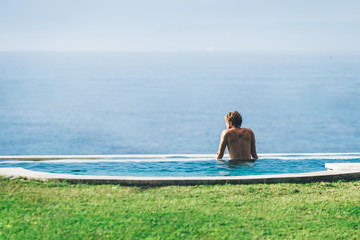 Handsome man relaxing in a pool near ocean