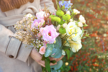 Closeup of female hands holding stylish bouquet of beautiful flowers