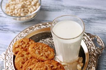 Peanut cookies with milk on tray on wooden background