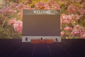 Blackboard on hardwood planks with flowers and brick wall background, vintage filtered tones