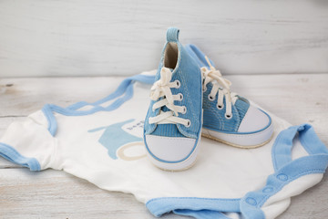 blue shoes for baby clothes and for a boy on a white wooden back