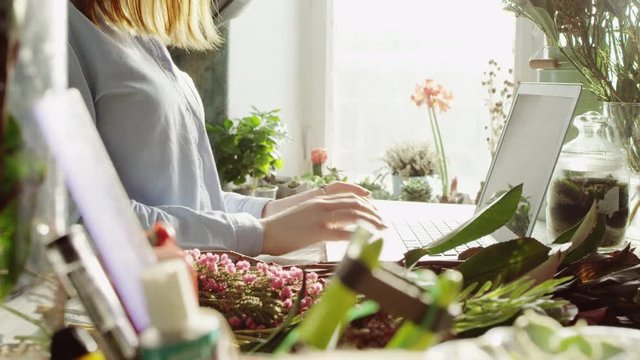 side view of smiling florist typing on laptop