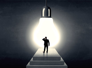 Man standing on a step in front of a huge light bulb