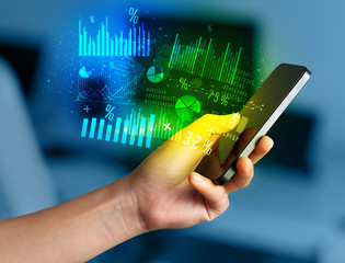 Hand holding smartphone with business diagrams