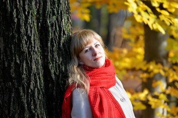 Portrait of the quiet young woman with a red scarf against the b