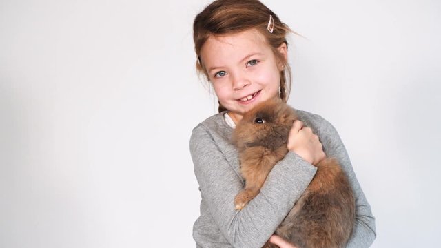 blondes m&auml;dchen spielt mit kaninchen indoor