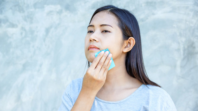 Women use oil remover paper on her face.